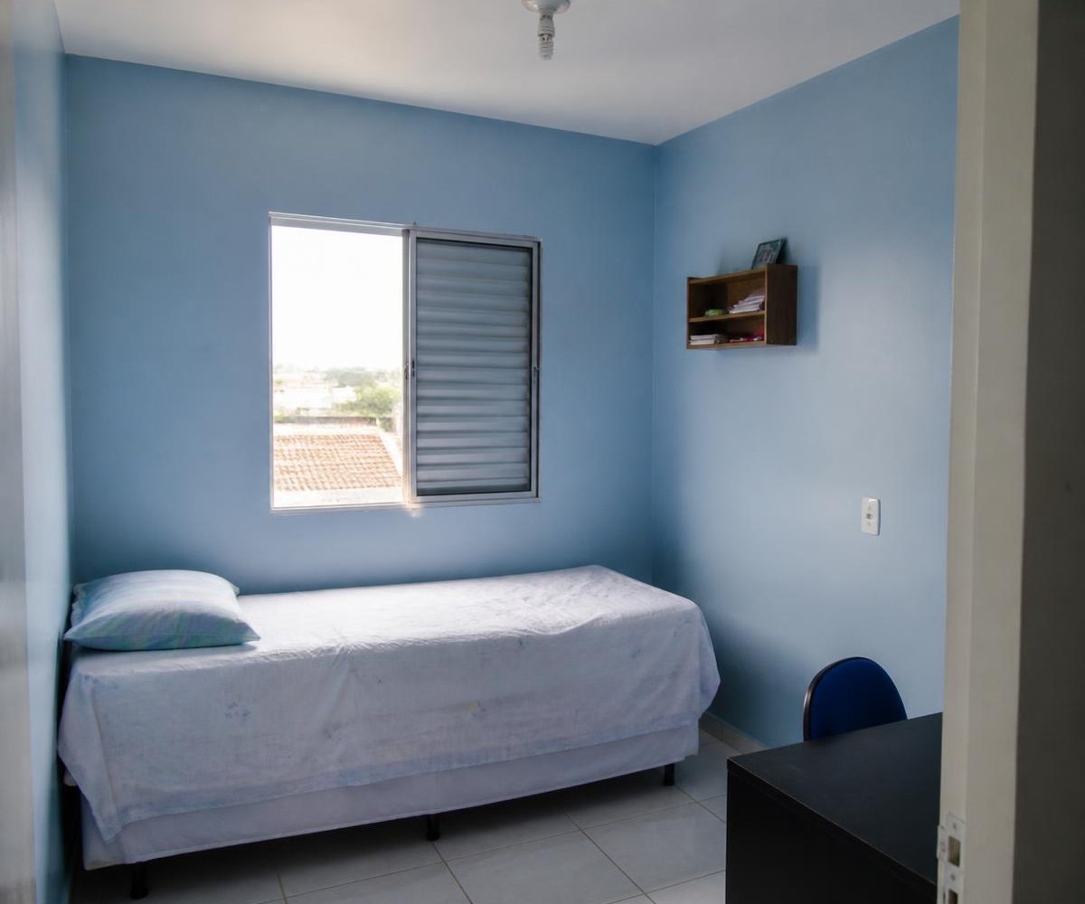 Quarto pequeno com paredes pintadas em azul claro e teto branco